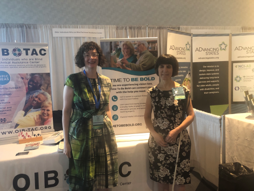 Polly and Kendra standing in front of the OIB-TAC booth at the 2023 USAging Conference