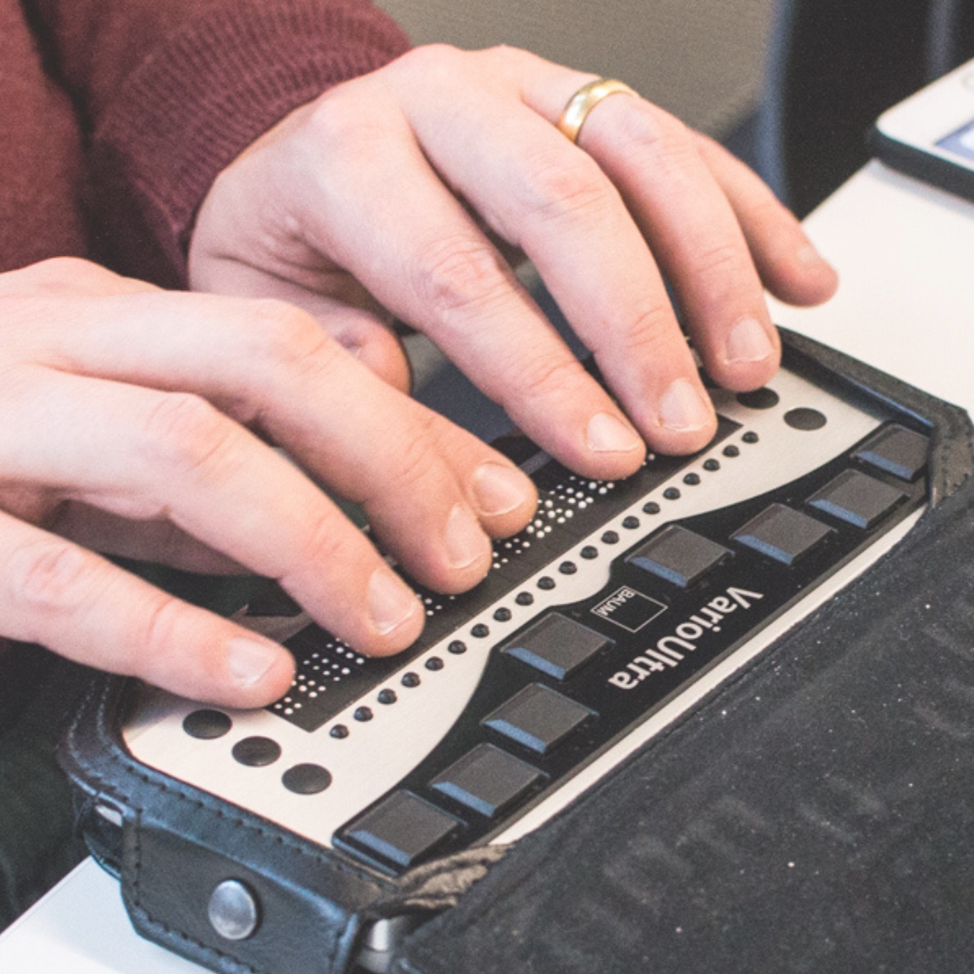 Close up of a pair of hands using an electronic braille device.